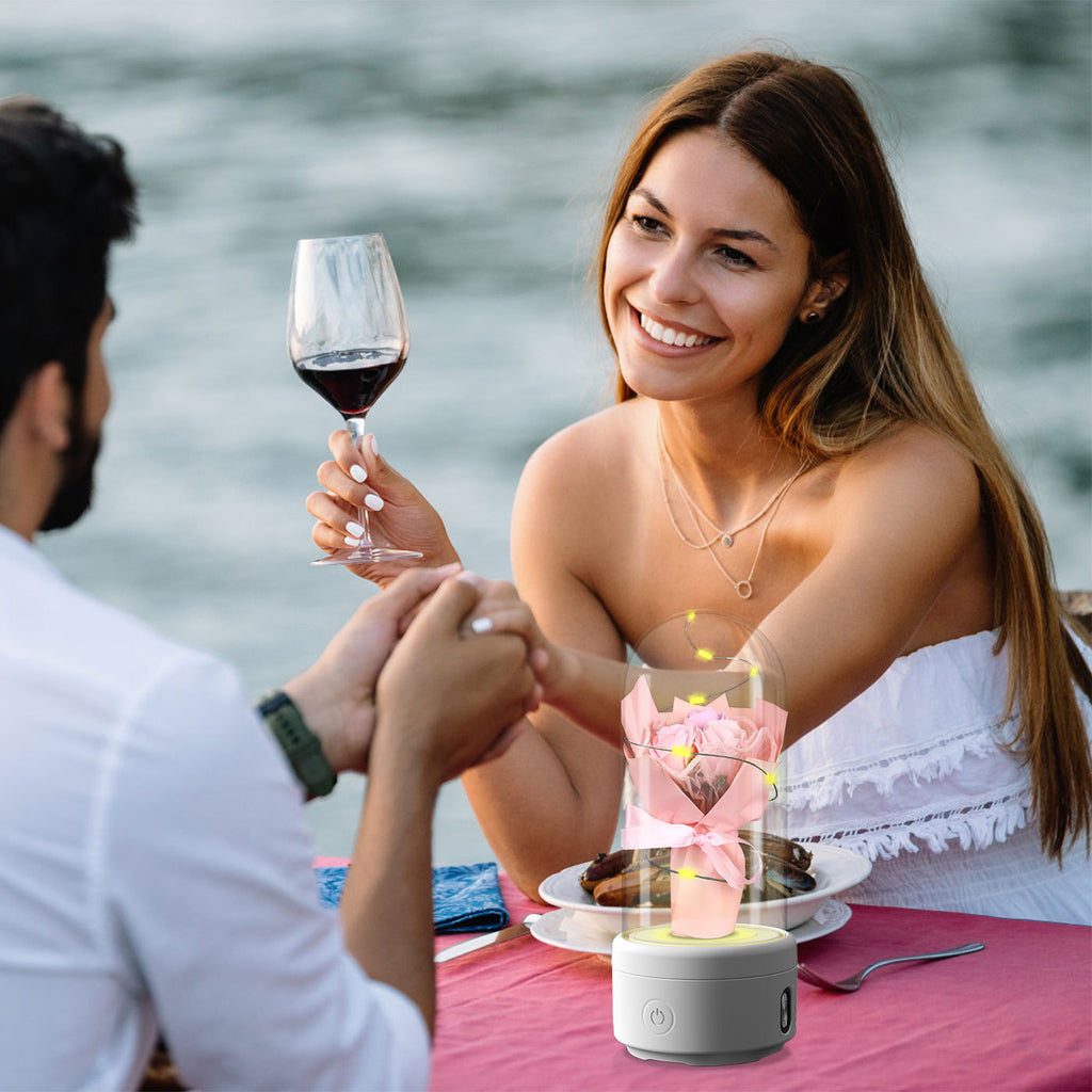 LED rose night light speaker on table during romantic outdoor dinner with couple holding hands