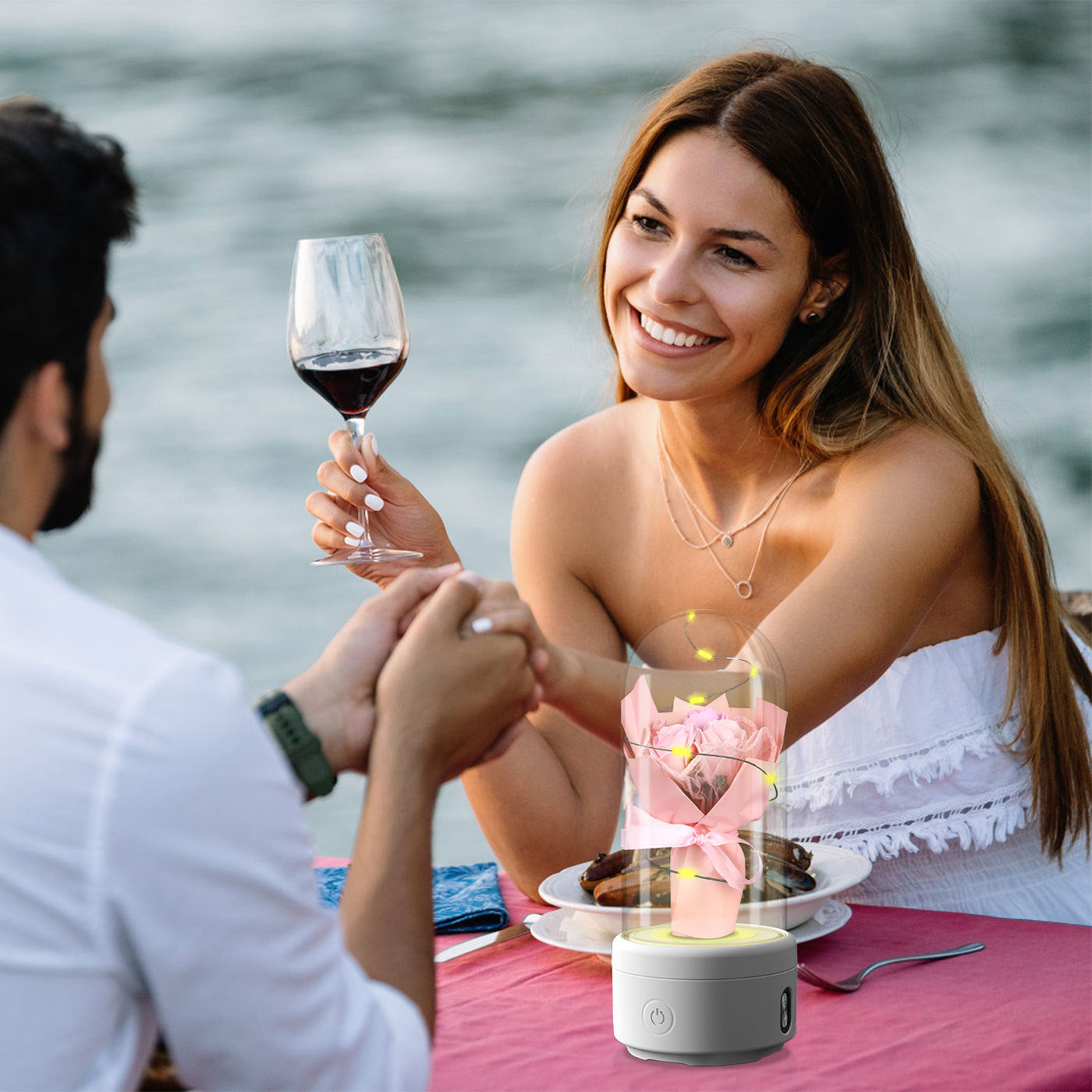 LED rose night light speaker on table during romantic outdoor dinner with couple holding hands