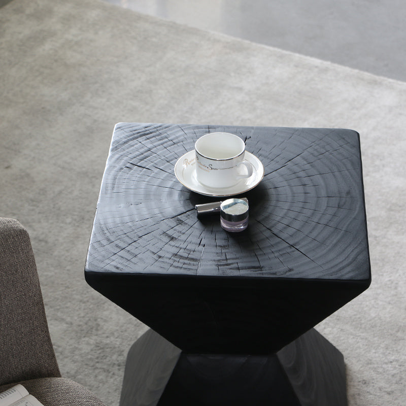 Shopi Vella black log sofa side table with visible wood grain holding a white teacup and nail polish