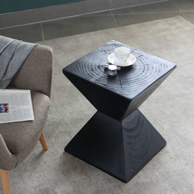 Shopi Vella black geometric log sofa side table with a cup and candle on top beside a gray sofa