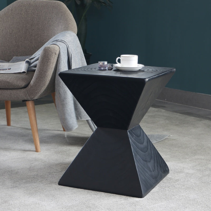 Shopi Vella black log sofa side table with geometric design placed next to a gray armchair