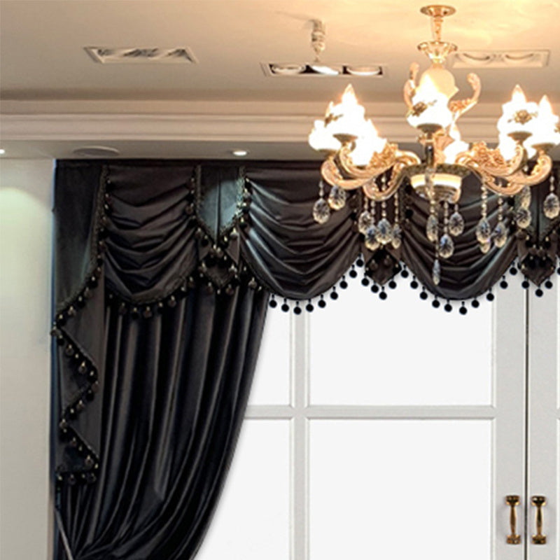 Shopi Vella luxury black velvet curtains with elegant tassel trim hanging by window under chandelier