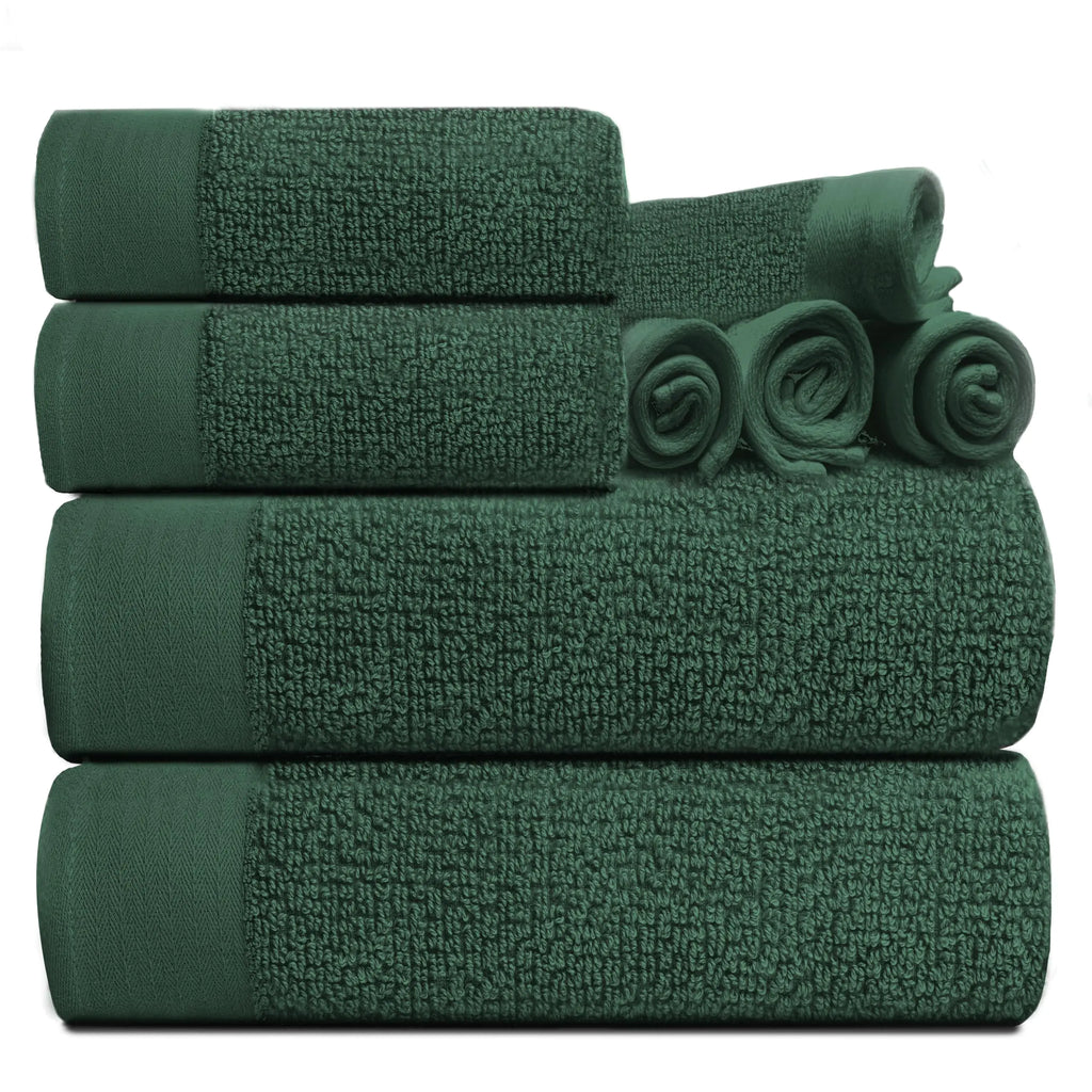 Dark green luxury cotton towel set neatly stacked with rolled and folded towels