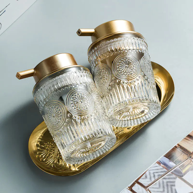 Luxury glass soap dispenser set with gold pump tops and intricate etched design on gold tray