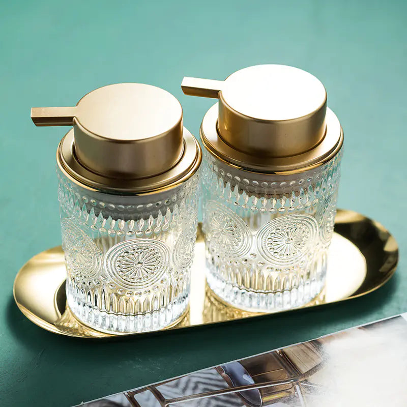 Luxury glass soap dispenser set with gold pump tops on a matching gold tray