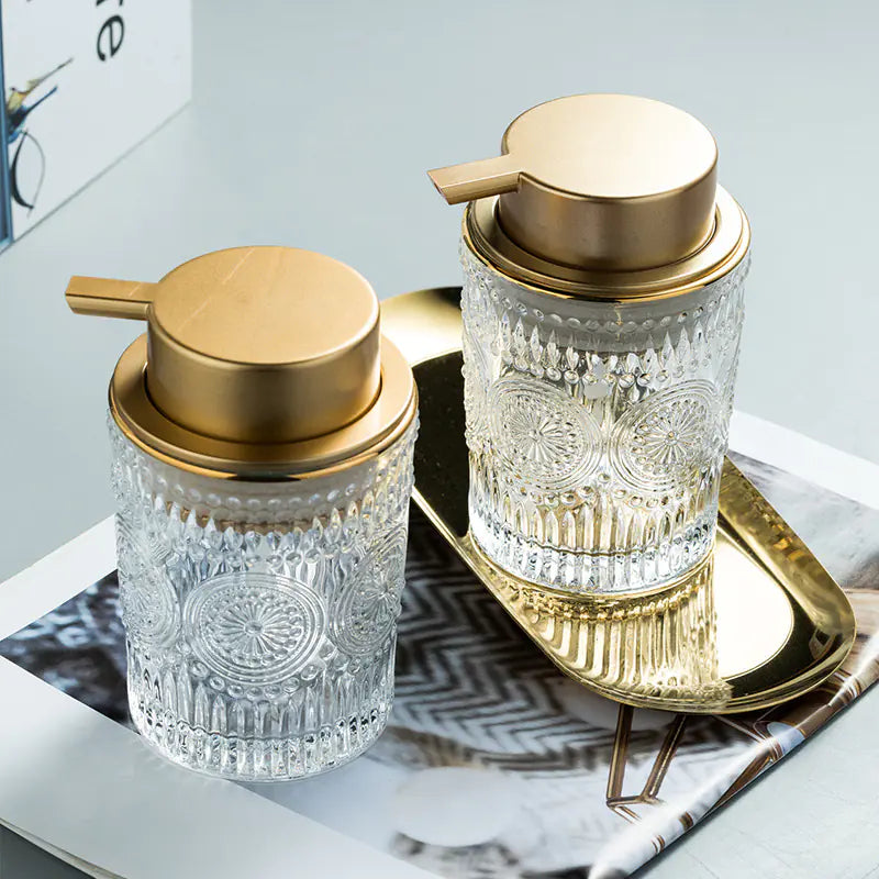 Luxury glass soap dispenser with gold pump and intricate cut glass design on gold tray