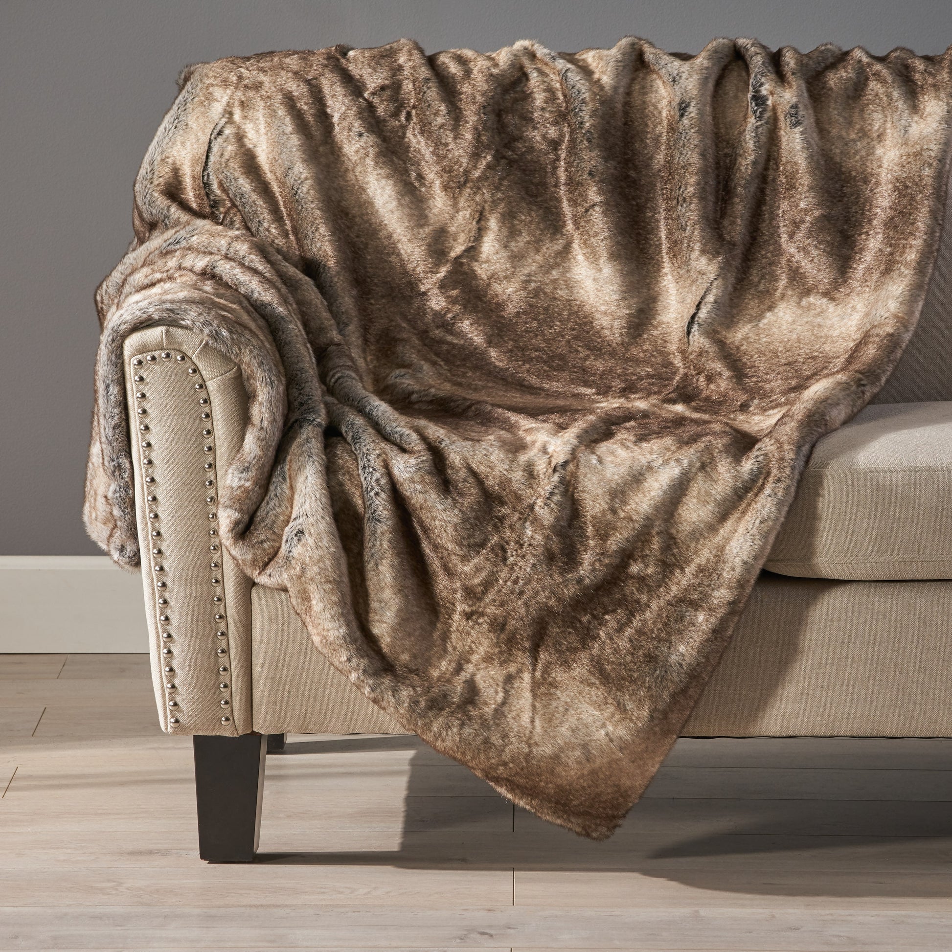 Shopi Vella luxury living room blanket draped over beige sofa with nailhead trim