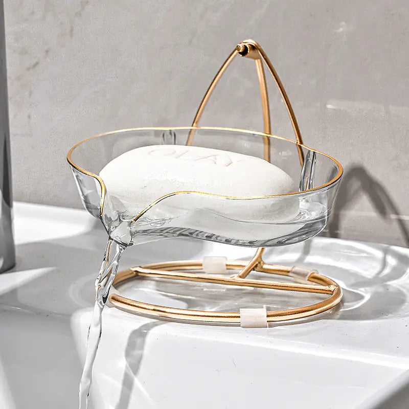 Luxury soap holder with drainage feature in clear tray and gold metal stand draining water