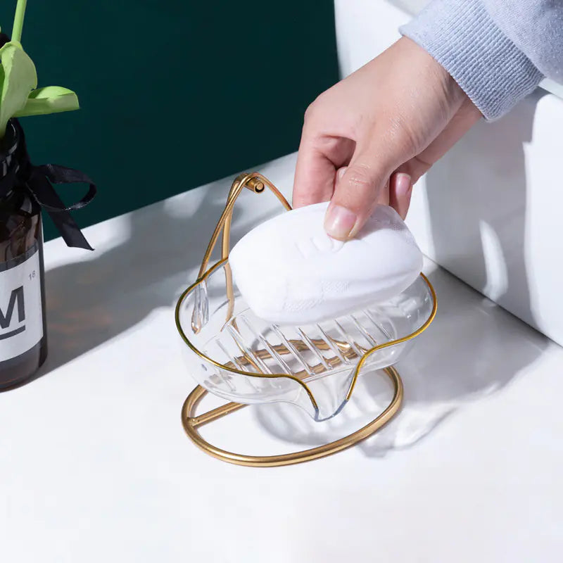 Luxury soap holder with drainage in clear glass and gold metal frame holding a white soap bar