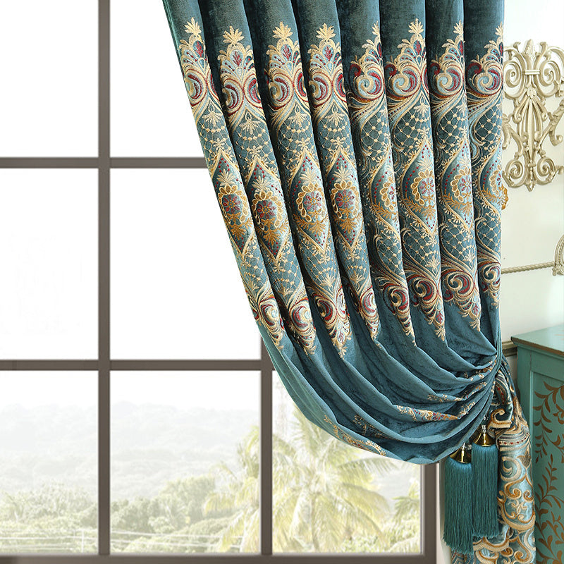 Shopi Vella luxury velvet blackout curtains in blue with intricate gold and red embroidery hanging by a window