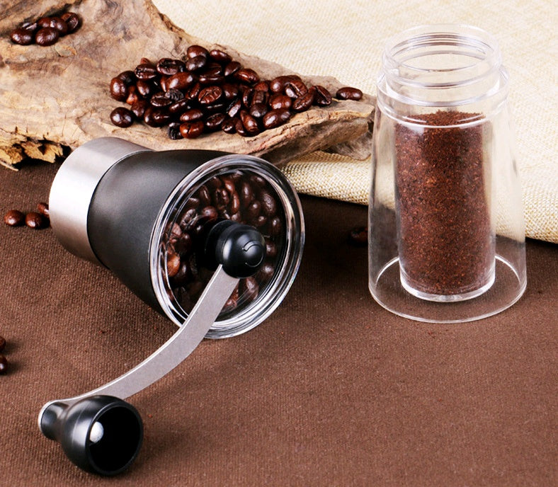 Shopi Vella manual coffee grinder with handle, coffee beans, and ground coffee container on brown surface