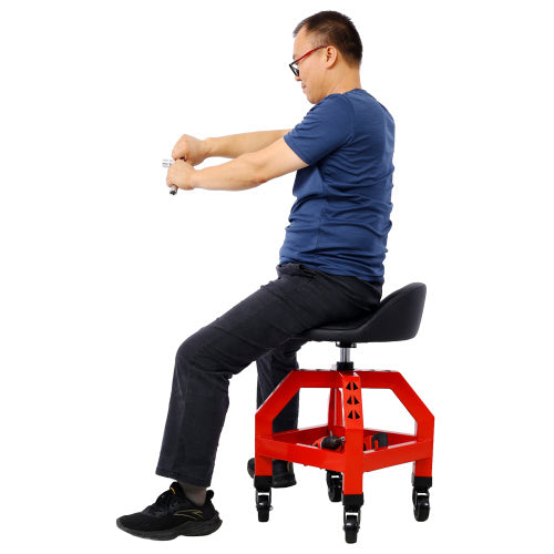 Man sitting on red mechanics rolling creeper seat with black cushion and wheels against white background