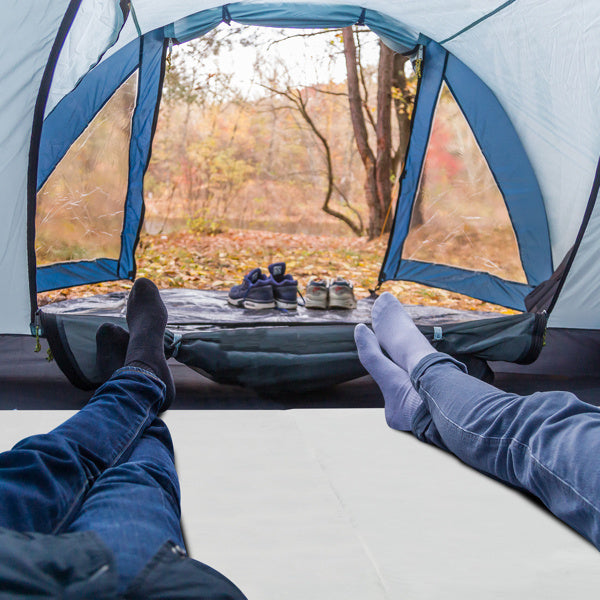 Two people relaxing inside a tent on a bed with a memory foam mattress topper enjoying the outdoor view