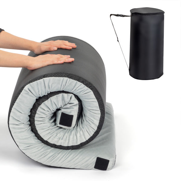 Rolled memory foam mattress topper in gray and black with hand pressing on it and black carrying case