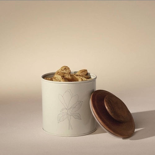 Shopi Vella metal canister with wooden lid filled with dried mushrooms on a beige background