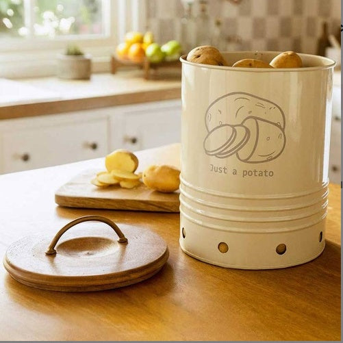 Shopi Vella metal potato storage bin in cream with wooden lid holding potatoes on kitchen table