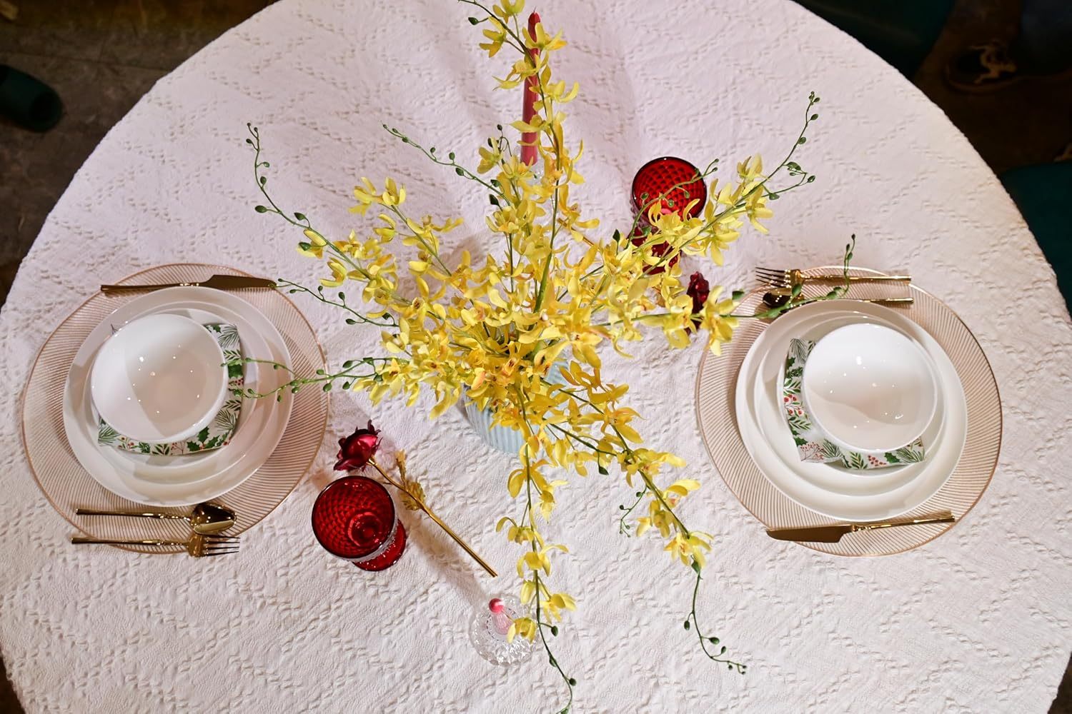 Shopi Vella microwave and dishwasher safe dinnerware set with plates, bowls, and gold-toned cutlery on a white tablecloth with yellow floral centerpiece
