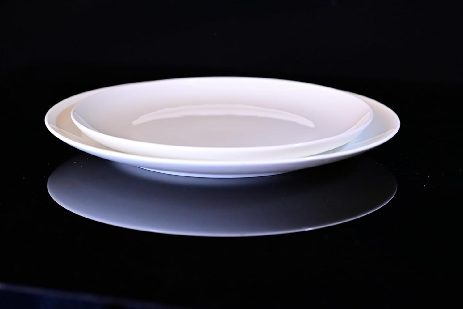 Shopi Vella white microwave and dishwasher safe dinnerware plates stacked on black surface