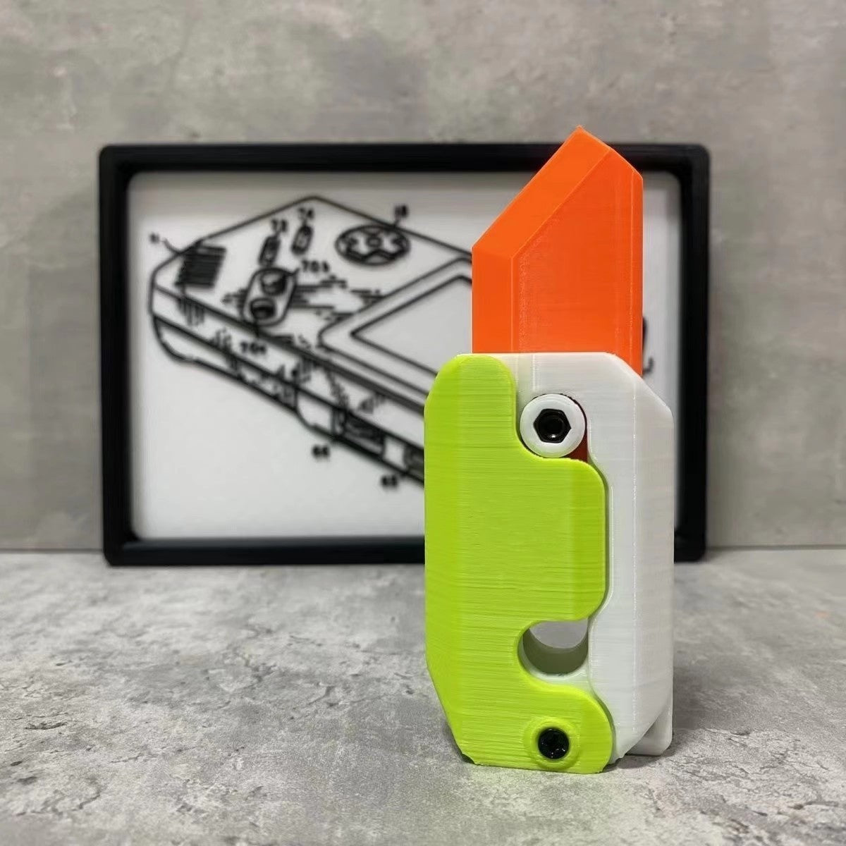 Shopi Vella mini 3D printing toy knife in green white and orange with detailed blade design on concrete surface