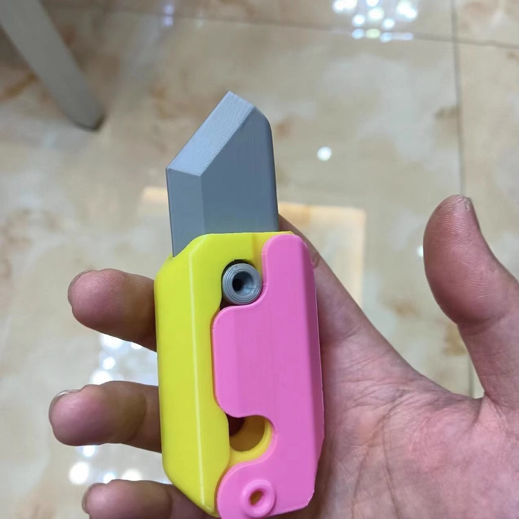 Shopi Vella mini 3D printing toy knife in yellow and pink held in hand with a gray blade