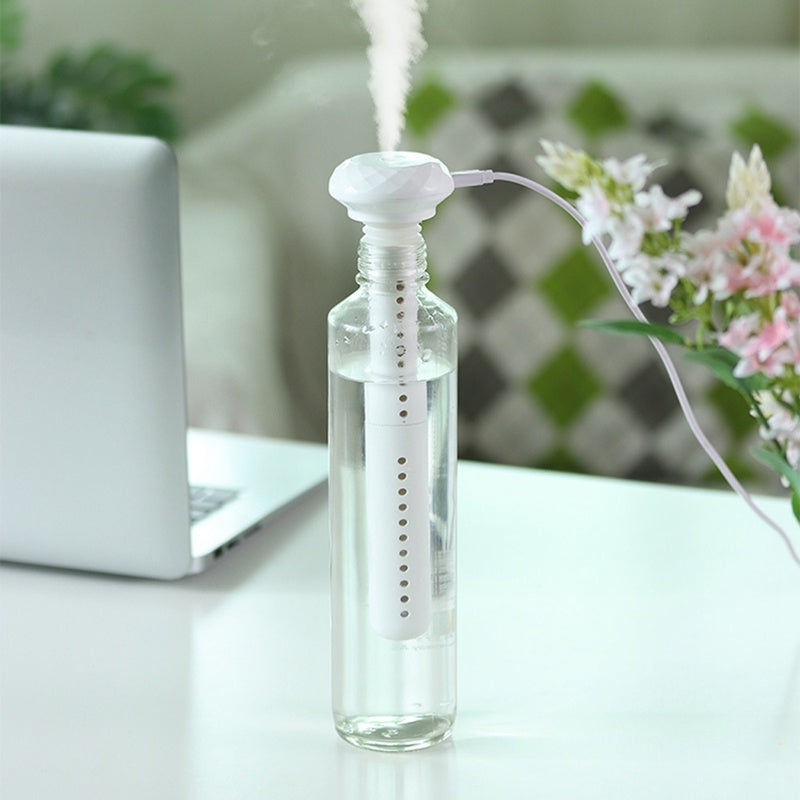 Shopi Vella mini USB humidifier releasing mist from a clear water bottle on a white desk