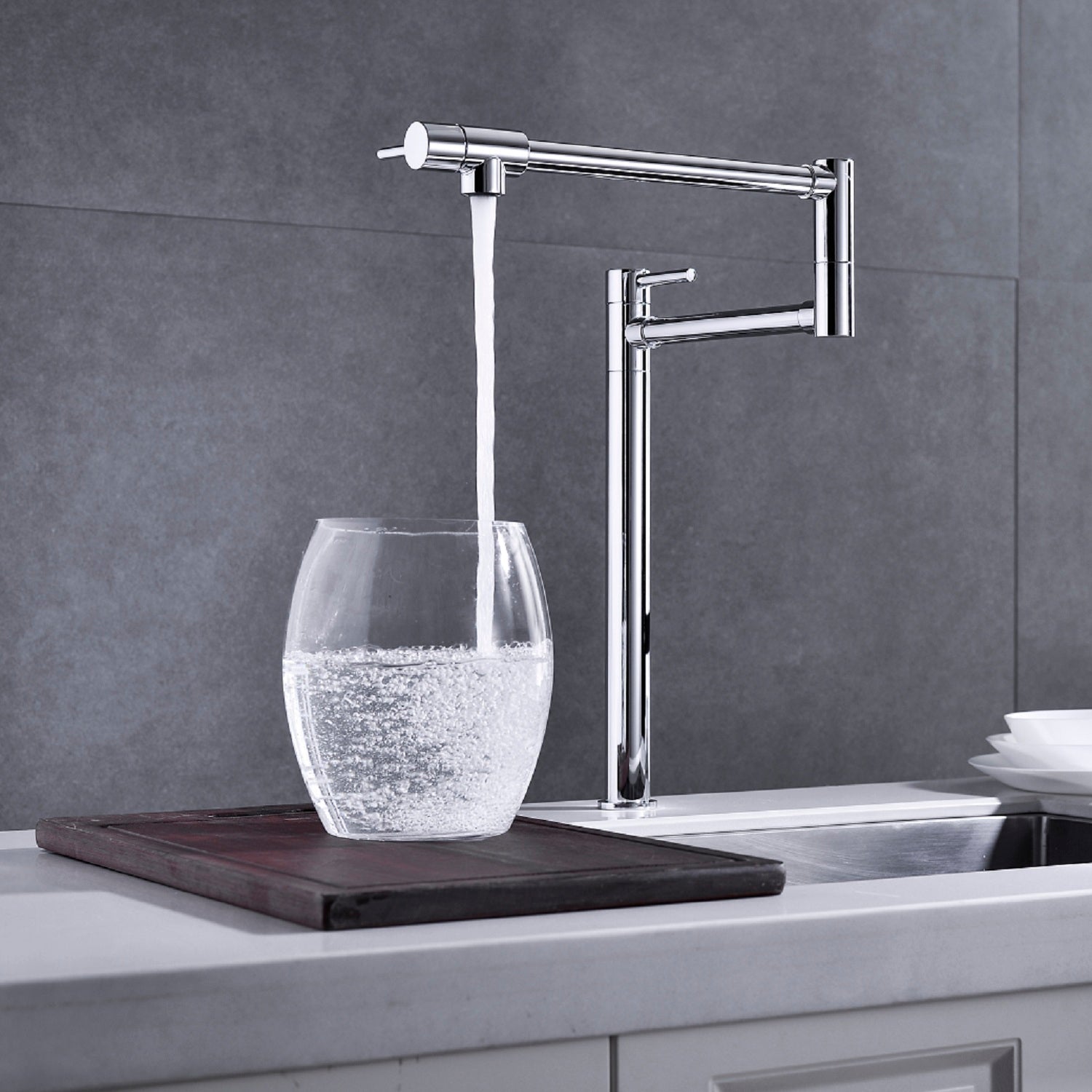 Shopi Vella modern folding sink faucet in chrome filling a glass with water over kitchen sink
