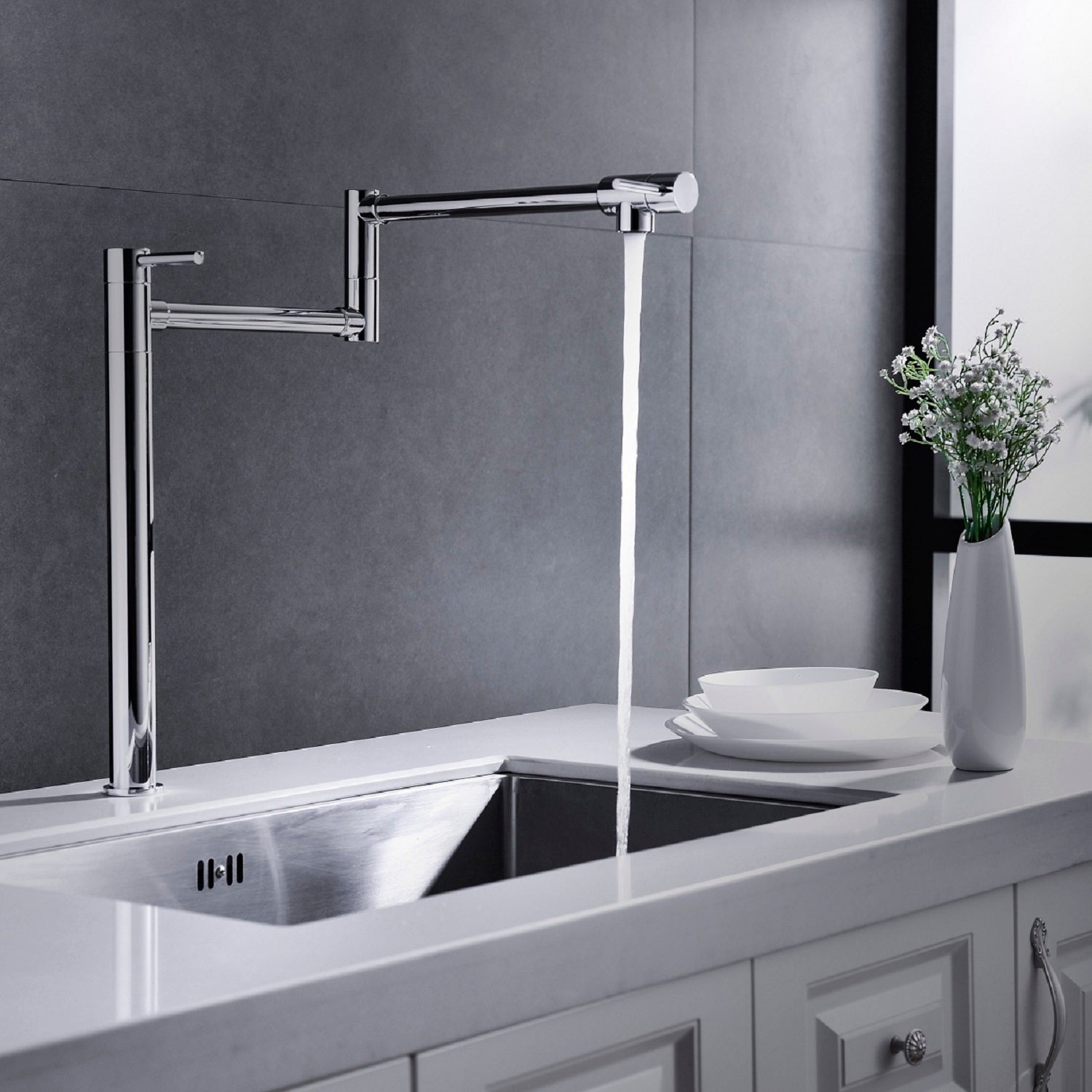 Shopi Vella modern folding sink faucet in chrome installed over a stainless steel kitchen sink with flowing water