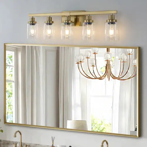 Modern gold vanity light fixture with five clear glass shades mounted above bathroom mirror