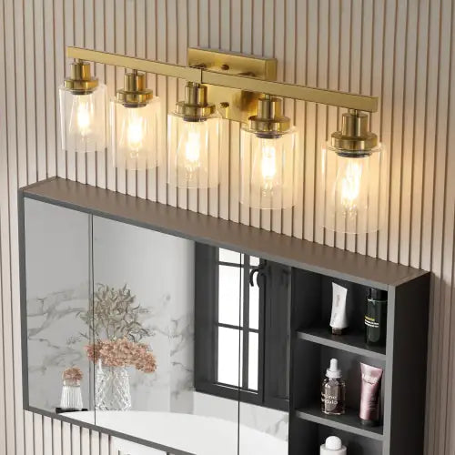 Modern gold vanity light fixture with five glass shades mounted above bathroom mirror