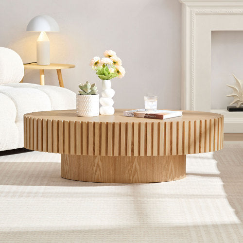 Shopi Vella modern handmade drum coffee table in light wood with decorative items in a cozy living room