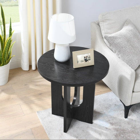 Modern solid wood coffee table by Shopi Vella with round black top and unique leg design in living room
