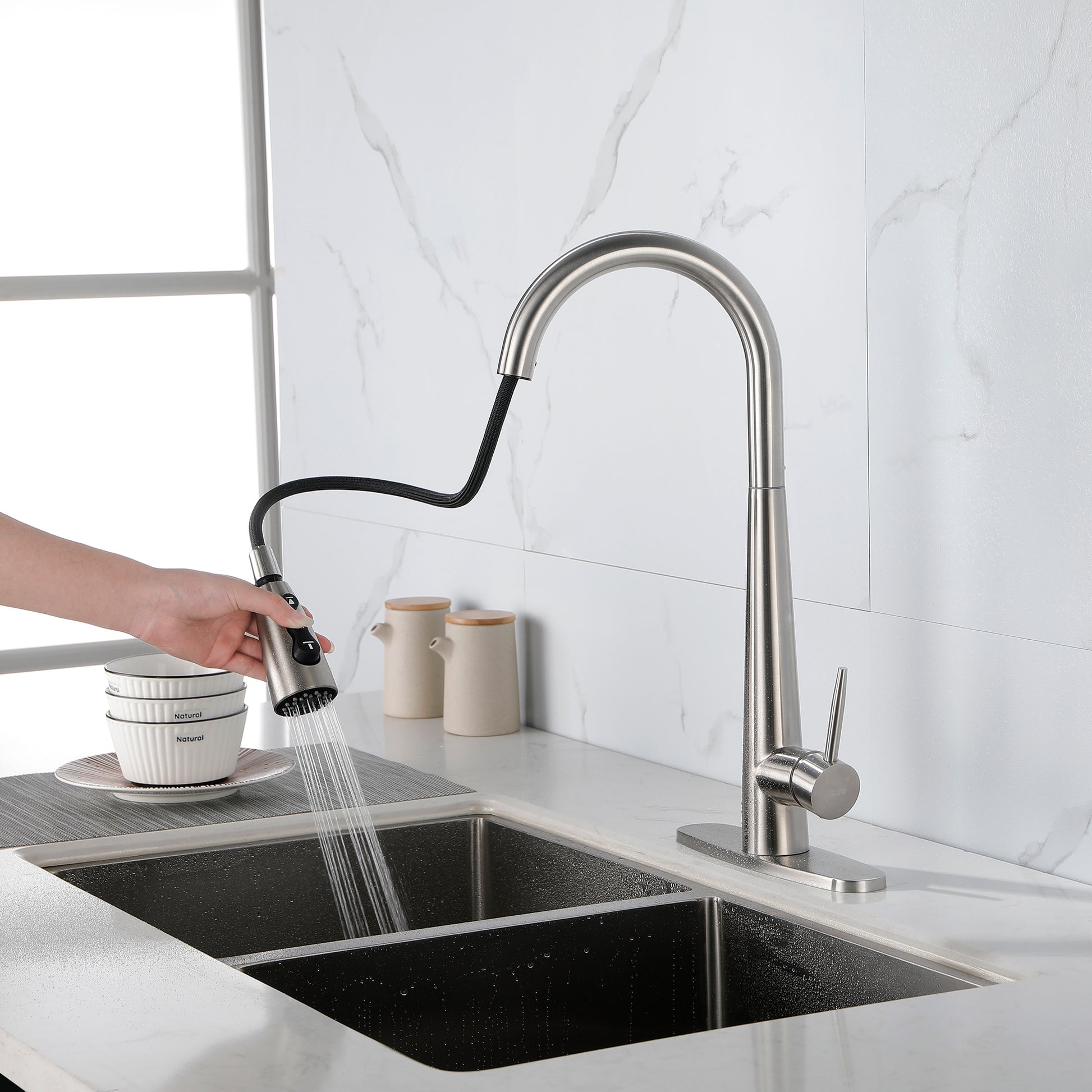Modern stainless steel kitchen faucet with pull-down spray head installed on white countertop by Shopi Vella