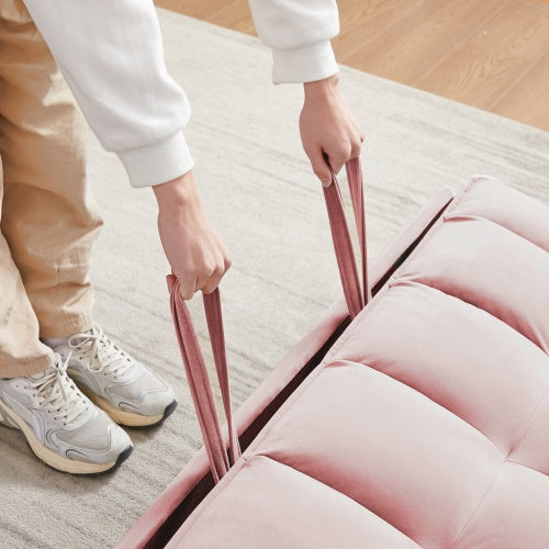Person pulling straps on a pink modern velvet loveseat sleeper sofa revealing the bed mechanism