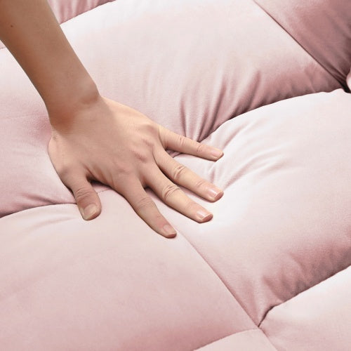 Hand pressing soft pink fabric of modern velvet loveseat sleeper sofa showing plush cushion comfort