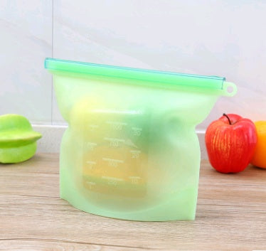 Shopi Vella green silicone food storage bag standing on wooden kitchen counter with fruits inside