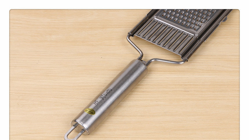 Shopi Vella multi-purpose grater and peeler with stainless steel handle on wooden surface