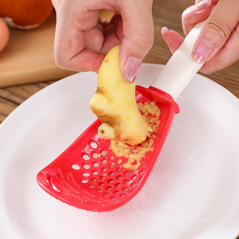Shopi Vella multifunctional slotted cooking spoon grating fresh ginger over white plate