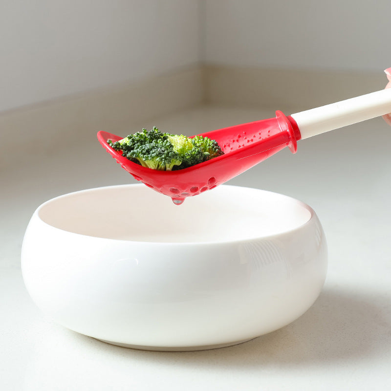 Shopi Vella multifunctional slotted cooking spoon holding broccoli over a white bowl