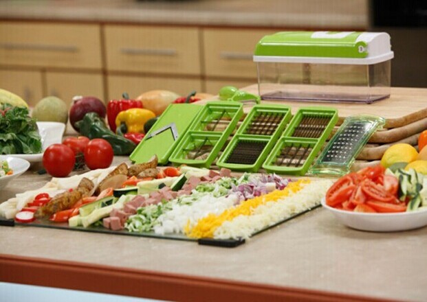 Shopi Vella multifunctional vegetable chopper with green blades and assorted chopped vegetables on kitchen counter
