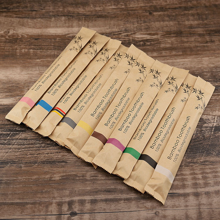 Pack of natural bamboo toothbrushes soft bristle in eco-friendly biodegradable paper sleeves on wooden surface
