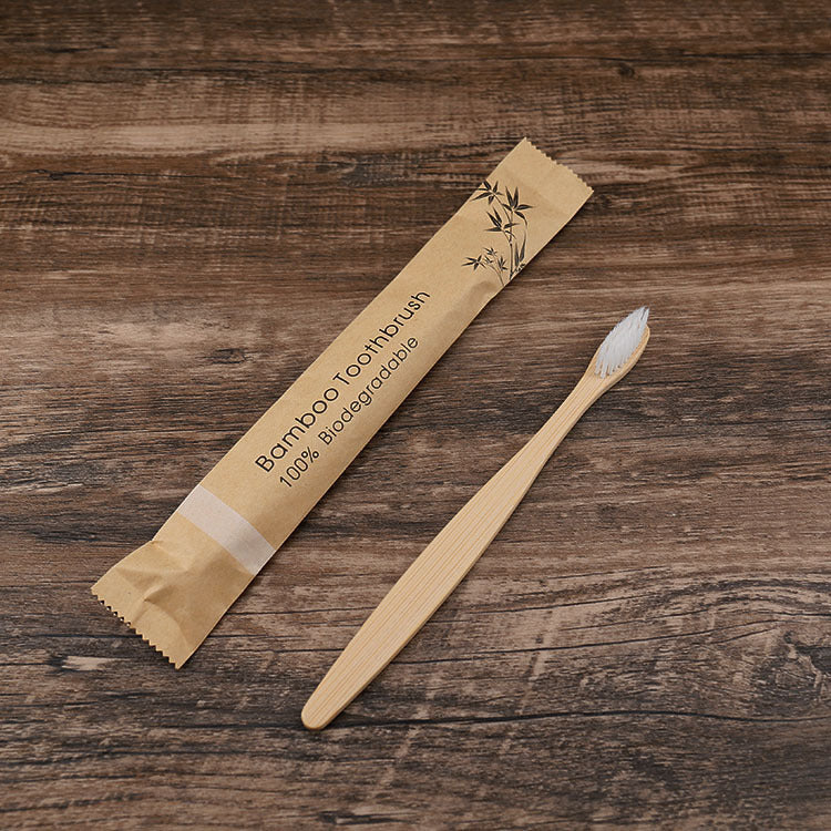 Natural bamboo toothbrushes soft bristle with biodegradable packaging on wooden surface by Shopi Vella