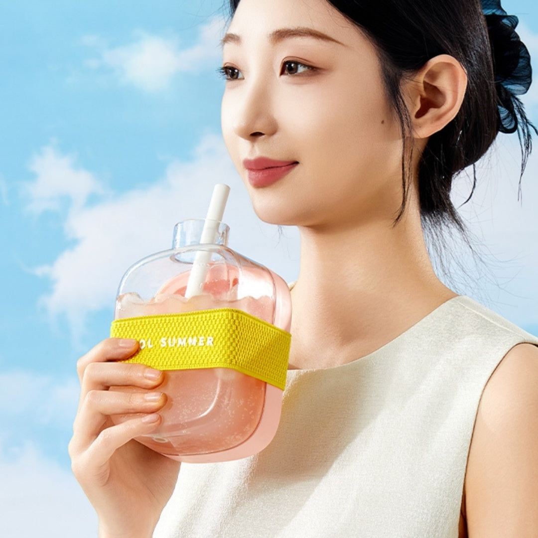 Woman holding a Shopi Vella one-click molding cooling cup with a yellow grip and white straw
