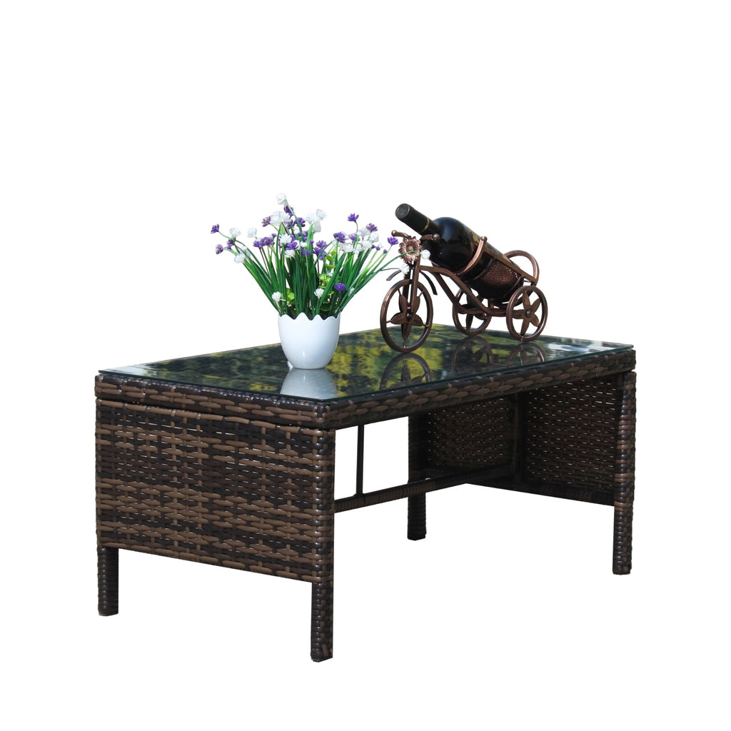 Shopi Vella outdoor patio coffee table with woven rattan design and glass top holding a flower pot and decorative wine holder