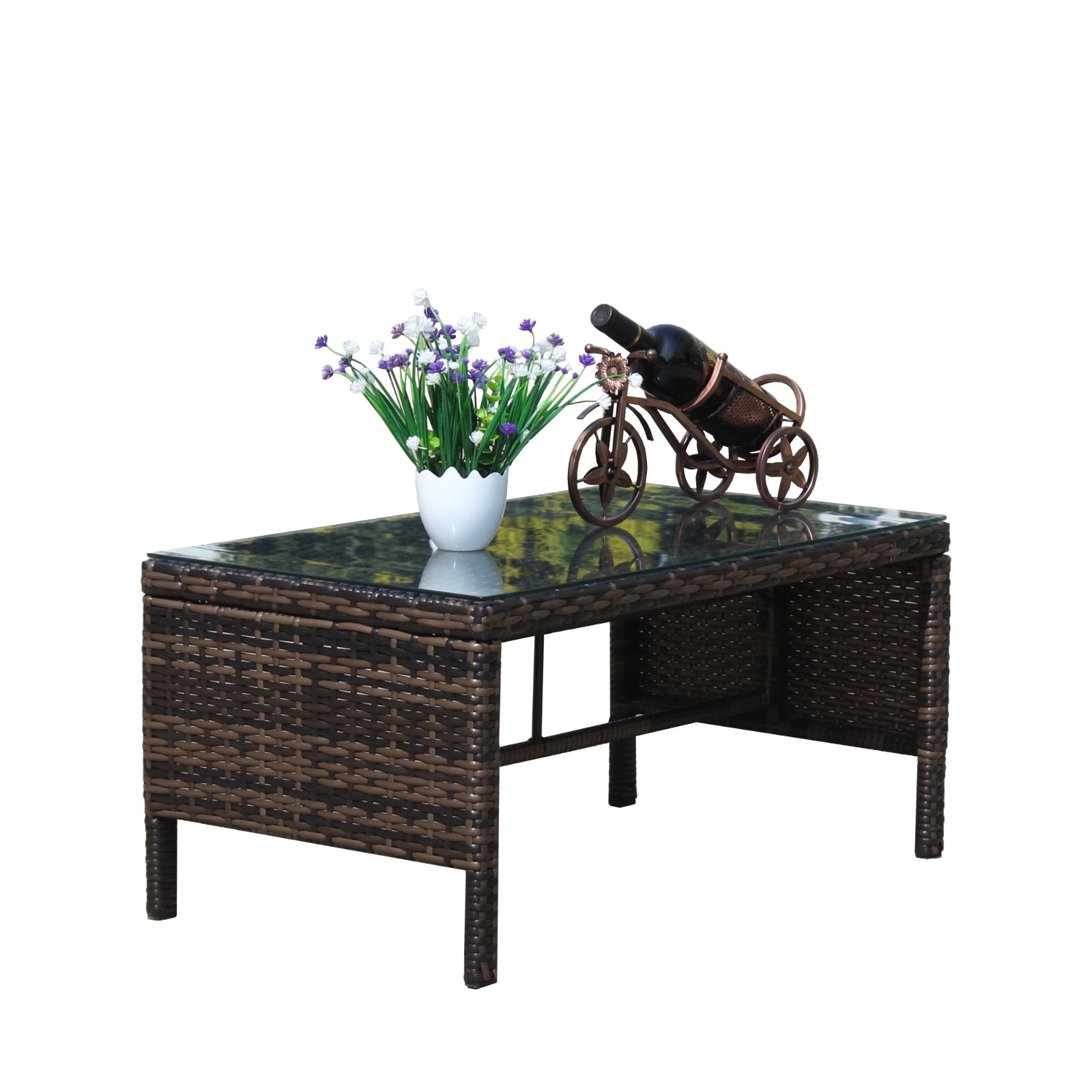 Shopi Vella outdoor patio coffee table with woven rattan design and glass top holding a flower pot and decorative wine holder