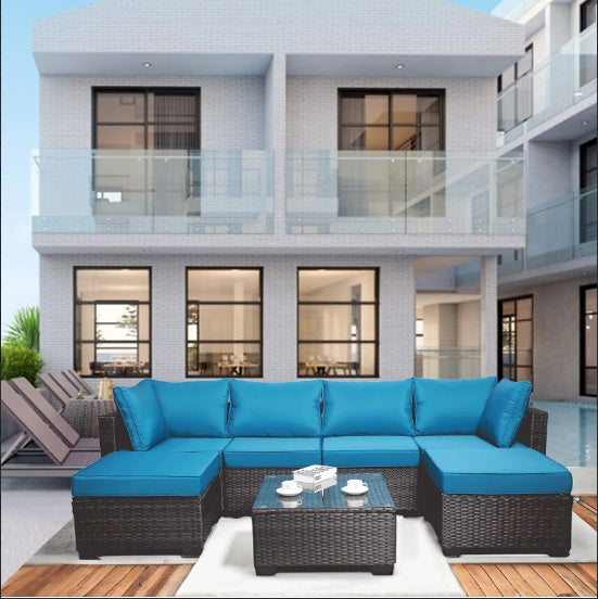 Outdoor sofa patio furniture with blue cushions and wicker frame on a patio with pool and modern house