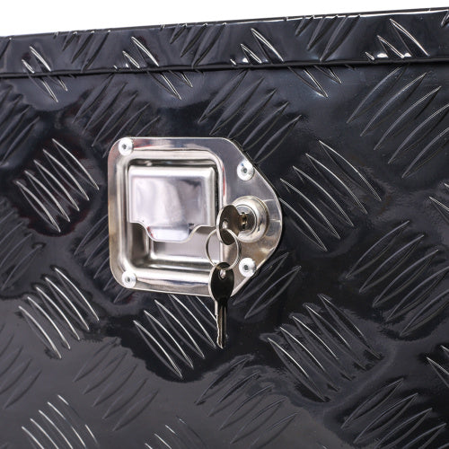 Close-up of black outdoor trailer underbody storage box lock with keys inserted on diamond plate surface