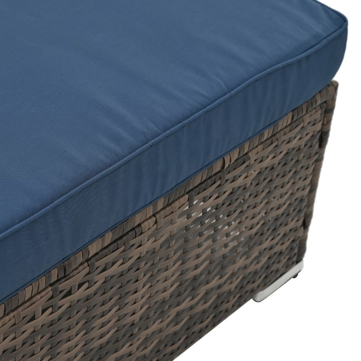 Close-up of outdoor wicker furniture with glass table featuring woven brown wicker and blue cushion