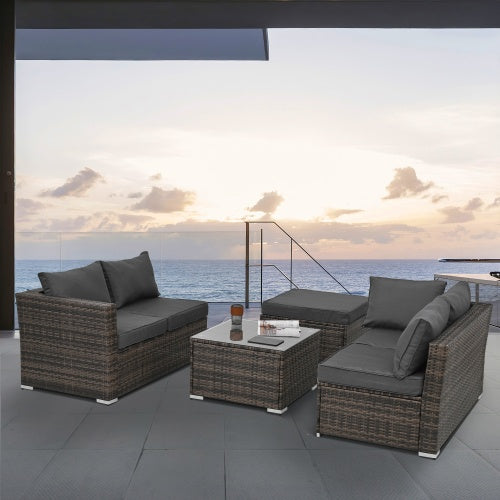 Shopi Vella outdoor wicker patio furniture set with dark gray cushions on a balcony overlooking the ocean at sunset