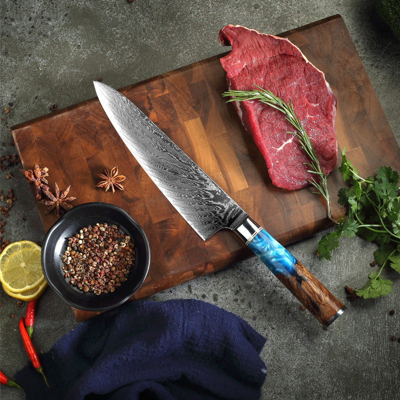 Shopi Vella pattern kitchen knife with a blue and wood handle next to raw steak and spices on a cutting board