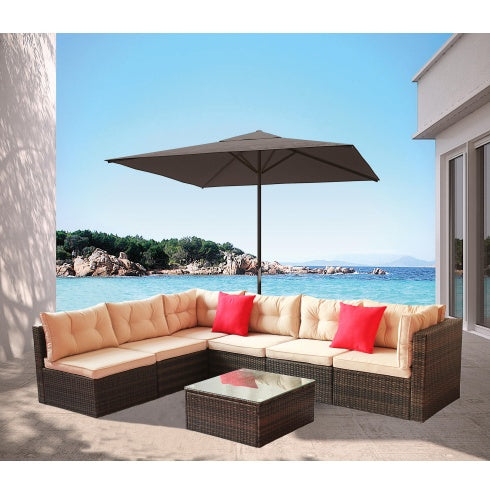 PE rattan garden corner furniture with beige cushions and red pillows under umbrella by sea